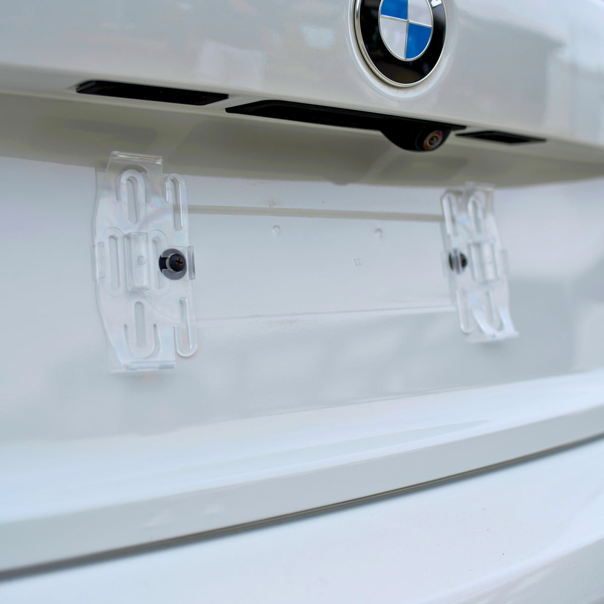 Clear PLEXICLICK® V1.3D UK clips screwed to the car's existing number plate mounting points